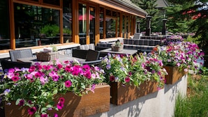An outdoor seating area with wooden planters filled with flowers, tables, and chairs.