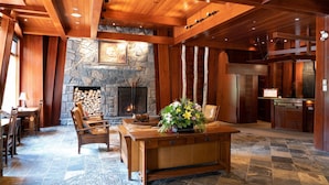 A spacious lobby with a stone fireplace, wooden ceiling beams, and a central reception desk.