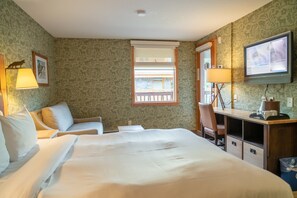 Une chambre d’hôtel avec deux lits, un bureau, une chaise, une télévision et une fenêtre donnant sur l’extérieur.
