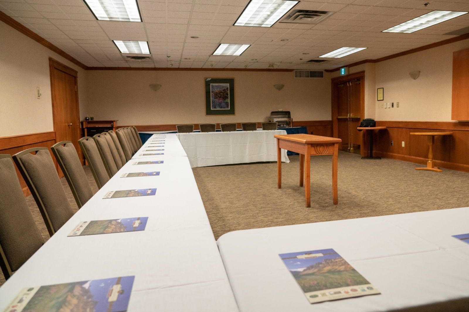 A conference room with a long table, chairs, and a small table in the center.