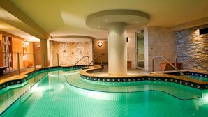A swimming pool with a circular design, a stone wall, and a glass door leading to a shower area. - Loft with Private Jetted Tub/Access to Spa (Banff)