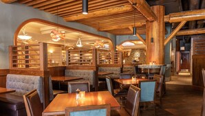 A cozy restaurant with wooden tables and booths, warm lighting, and a rustic interior. - Accessible room, Central Banff, Hot Pool! (Banff)