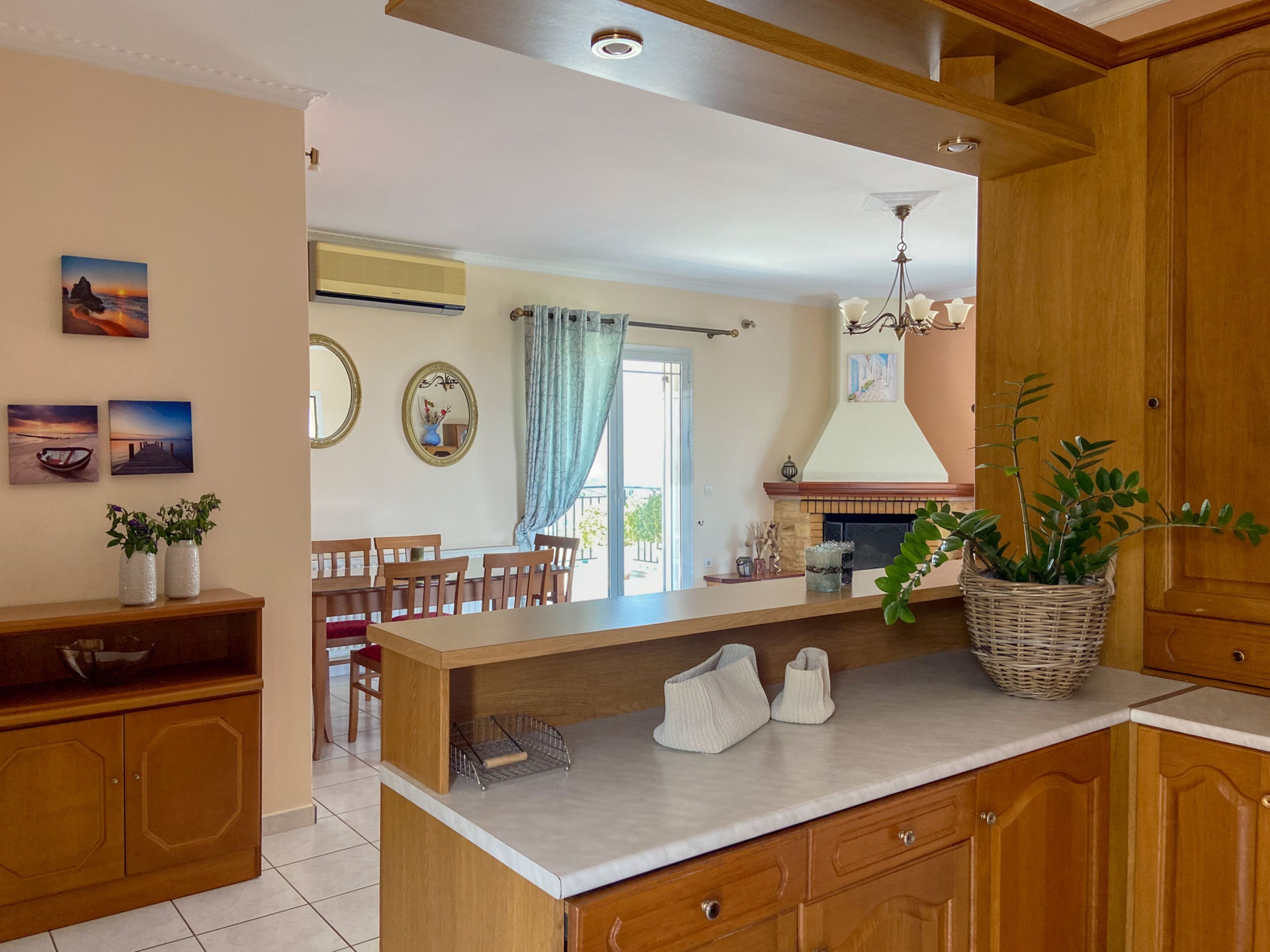 A kitchen with wooden cabinets, a marble countertop, and a dining area with a table and chairs.