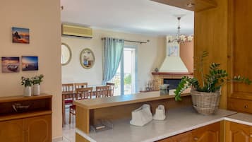 A kitchen with wooden cabinets, a marble countertop, and a dining area with a table and chairs.