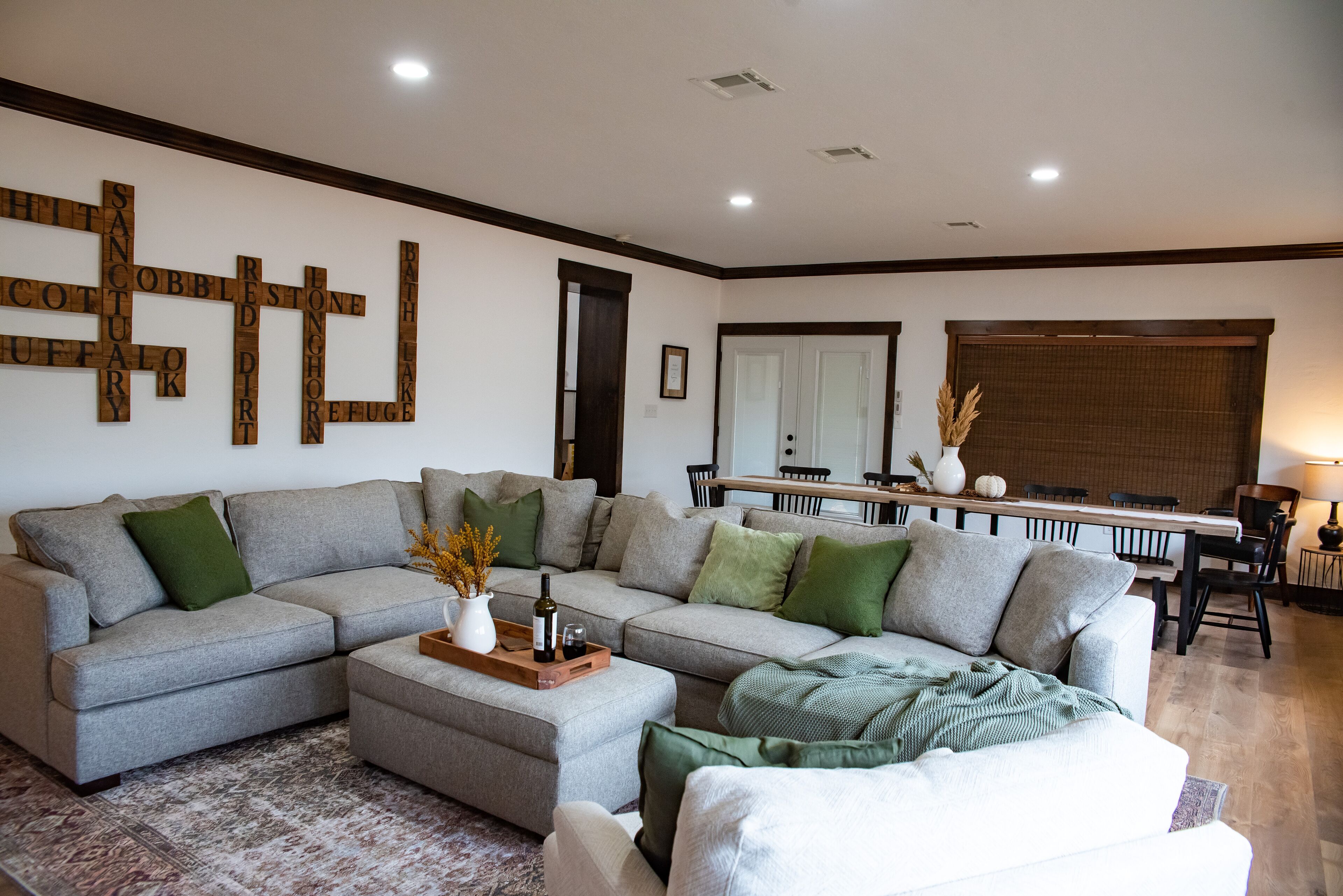 Ein modernes Wohnzimmer mit einem Ecksofa, einem Couchtisch und einem Essbereich mit Holztisch und Stühlen.