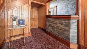 A wooden interior with a staircase, a reception desk, and a stone wall. - St Magnus Bay Hotel (Hillswick)