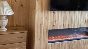 A wooden wall with a flat-screen TV mounted above a fireplace. - St Magnus Bay Hotel (Hillswick)
