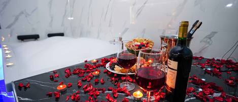 A table set with a bottle of wine, glasses, a plate of food, and candles.