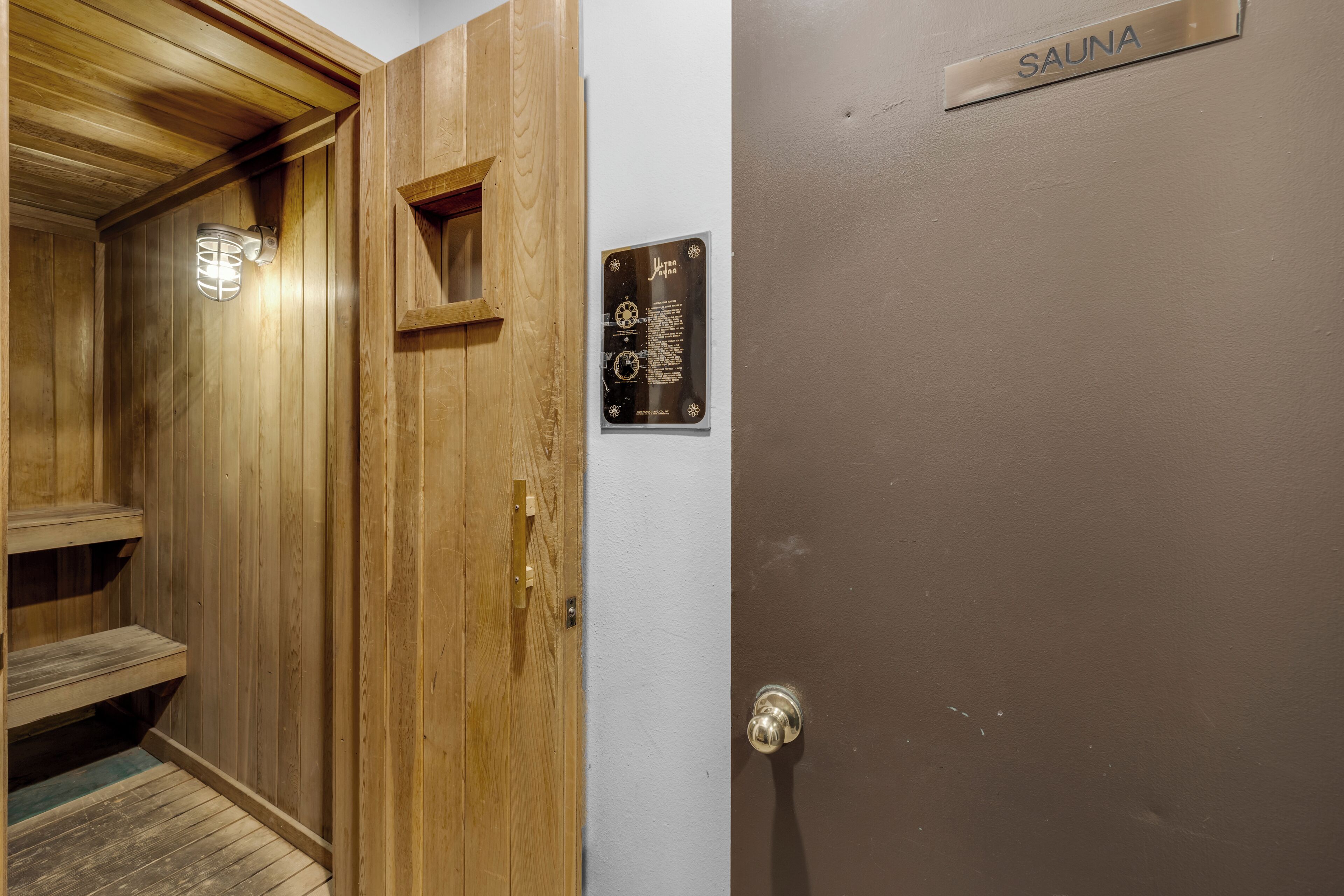 Une cabine de sauna en bois, avec une enseigne indiquant « SAUNA » et une plaque portant une inscription.