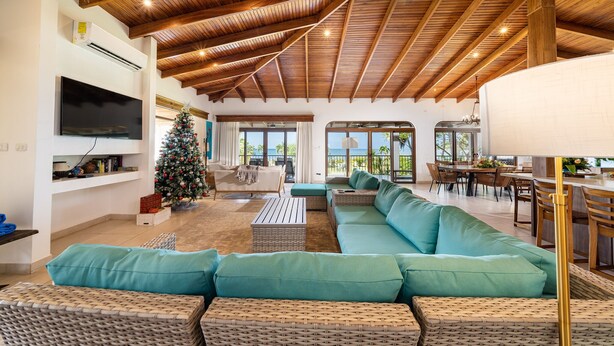 A spacious living area with a high wooden ceiling, a large sofa, a television, and a Christmas tree. - Villa Potrero Luxury Private Beachfront Home with Housekeeper, Concierge (Provincia de Guanacaste)