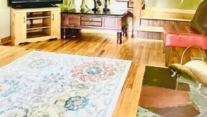 A living room with a wooden staircase, a television, and a red sofa. - Cozy Private home (Warrensburg)