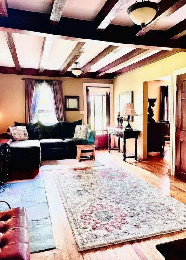 A cozy living room with a sofa, a rug, and a wooden floor.