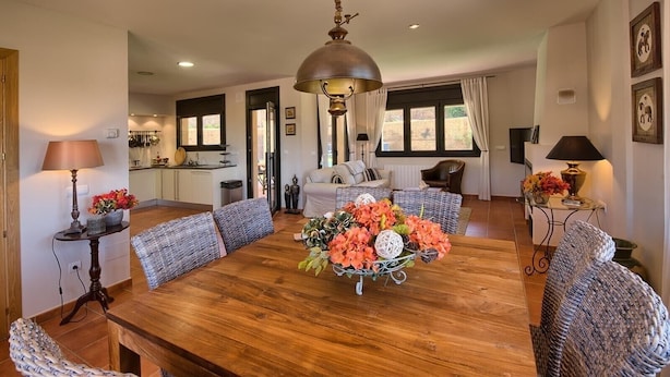 Un comedor amplio con una mesa de madera, sillas de mimbre y una lámpara colgante.