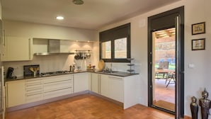 Una cocina con armarios blancos, una estufa a gas y una ventana con vistas a un patio.