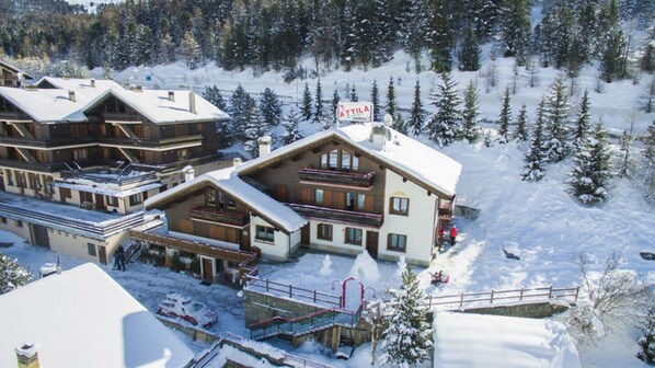 A snow-covered lodge with multiple buildings, a ski lift, and a sign indicating 'ATTILA.'