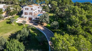 A large, white villa with a swimming pool, surrounded by lush greenery and a clear view of the sea. - Villa 'Font de Sa Cala' with Sea View, Wi-Fi and Air Conditioning (Provensals)