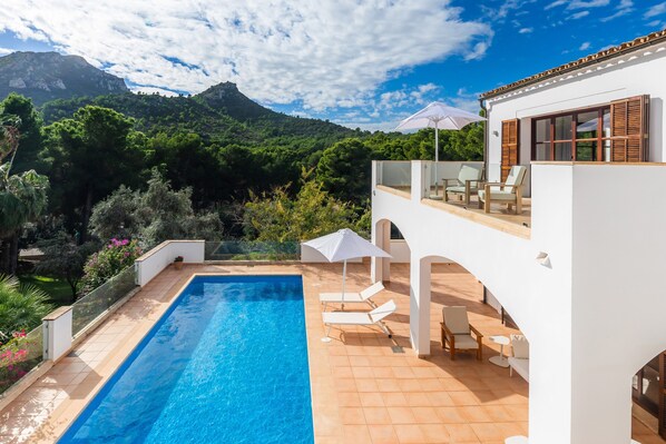 Una villa moderna con piscina, mobiliario exterior y vistas a la montaña.