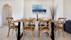 A dining area with a table, chairs, and a painting on the wall. - Apartment 'Christine's House' with Private Pool, Wi-Fi and Air Conditioning (Zakynthos)