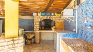 A stone fireplace with a tiled backsplash, a wooden ceiling, and a small television mounted above it.