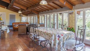 A dining area with a long table, chairs, and a ceiling with exposed beams.