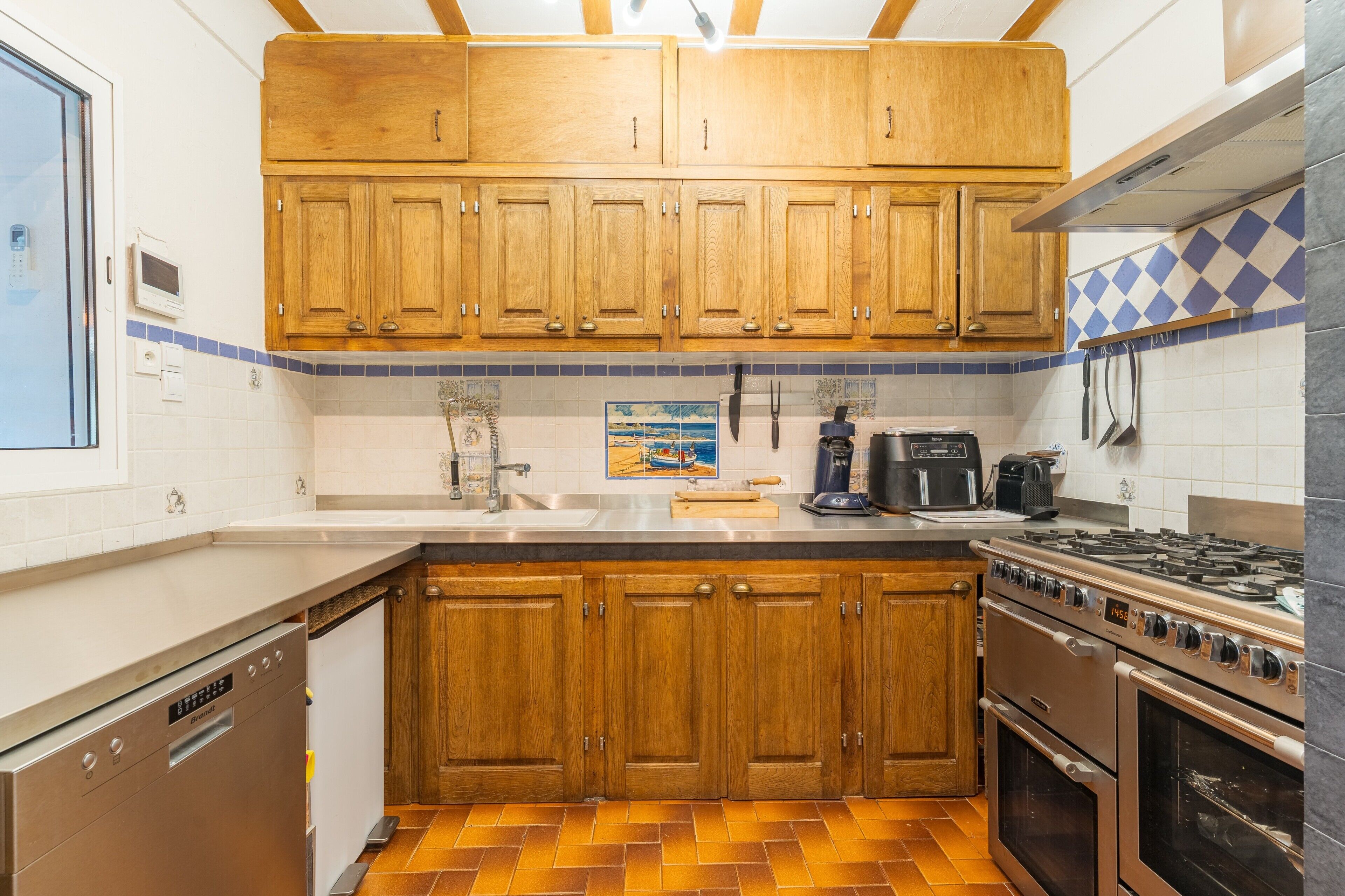 A kitchen with wooden cabinets, a stainless steel dishwasher, a stove, and a tiled backsplash.