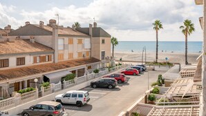 Un hôtel situé sur la côte, doté d’un parking, offrant une vue sur la plage et agrémenté de palmiers.