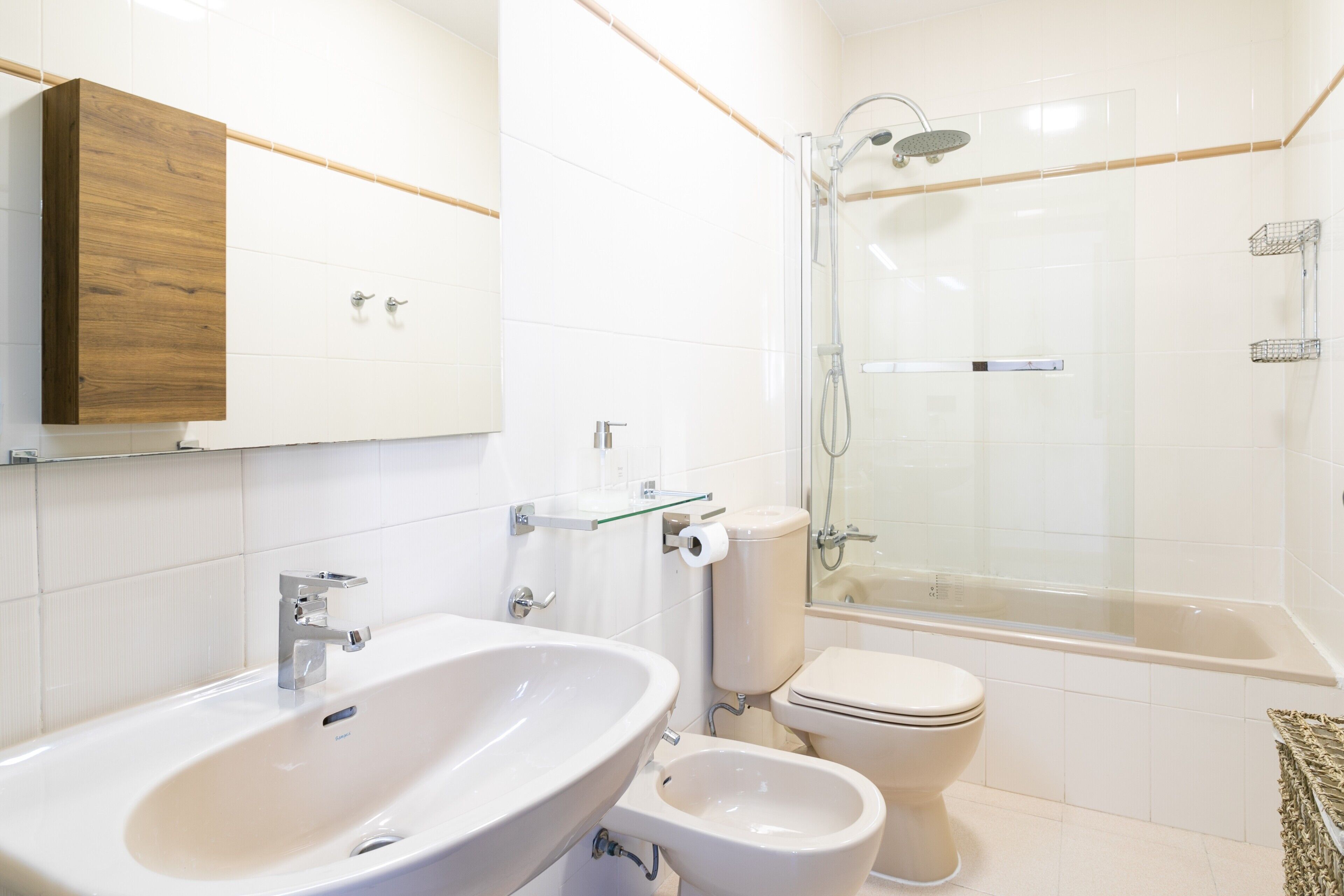 Une salle de bain moderne dotée d’un grand lavabo, de toilettes, d’un bidet et d’une douche à parois de verre.