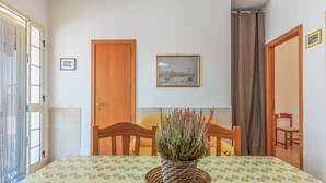 A room with a bed, a dining table with a plant, wooden chairs, a framed picture on the wall, and a door. - Pet-Friendly Holiday Home 'Casa Nico' close to the Sea with Terrace (Augusta)