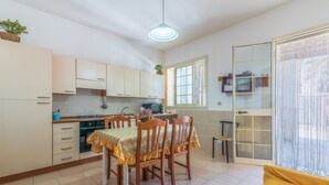 A compact kitchen with a dining table, chairs, and a sliding glass door leading to a balcony. - Pet-Friendly Holiday Home 'Casa Nico' close to the Sea with Terrace (Augusta)