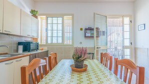 A dining area with a table, chairs, a potted plant, and a kitchen with cabinets and a microwave. - Pet-Friendly Holiday Home 'Casa Nico' close to the Sea with Terrace (Augusta)