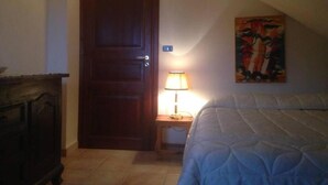 A bedroom with a bed, a door, a nightstand with a lamp, and a painting on the wall. - Apartment 'Residence Lithos' with Mountain View, Garden and Wi-Fi (Petralia Soprana)