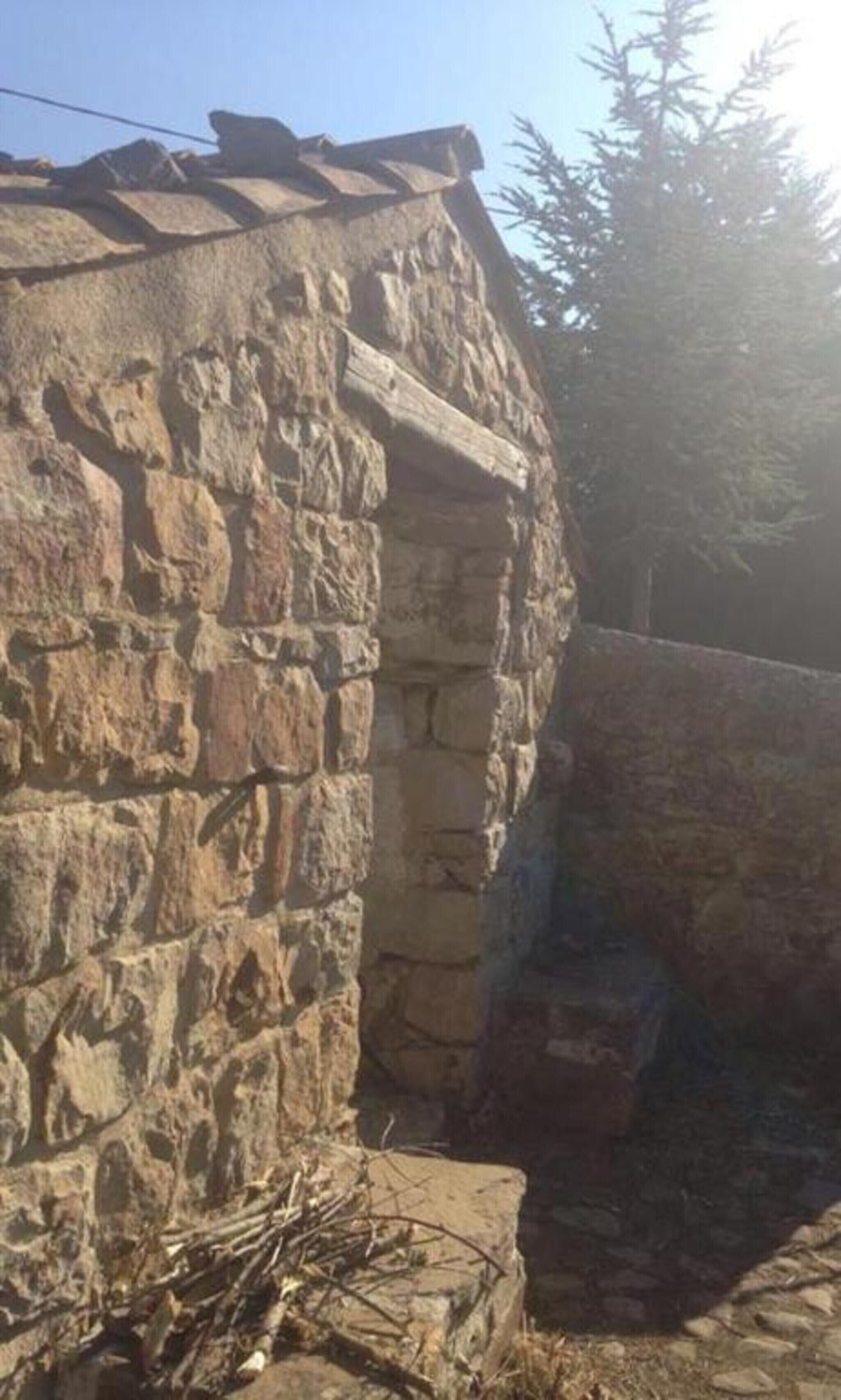 Um edifício de pedra com telhado inclinado e uma entrada pequena.