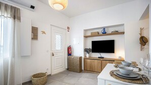 Eine moderne Küche mit Flachbildfernseher, Holzschränken und einem Essbereich mit Tisch für zwei Personen.