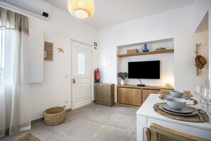 A modern kitchen with a flat-screen TV, wooden cabinets, and a dining area with a table set for two.
