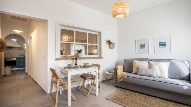 Eine moderne Küche mit Essbereich, einem grauen Sofa und einem Fenster mit Blick.