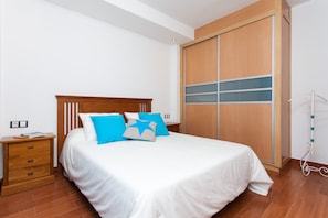 Une chambre bien rangée, avec un lit, une table de chevet en bois, une armoire et un vélo.