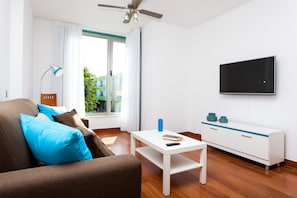 Un salon moderne avec un canapé, une table basse, un téléviseur et une fenêtre avec des rideaux.