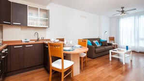 A modern kitchen with wooden cabinets, a dining table with chairs, a sofa, and a ceiling fan. - Vacation Home "Corralejo Main Street" with Terrace & Wi-Fi (Corralejo)