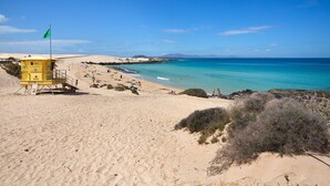 A beach with a lifeguard tower, clear blue sky, and calm sea.