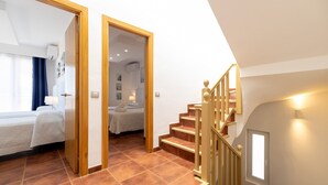A bedroom with a bed, a bathroom with a shower, and a staircase with a railing.