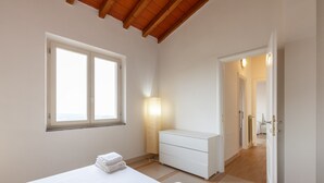 Un dormitorio con cama, mesita de noche, lámpara, cómoda y ventana.