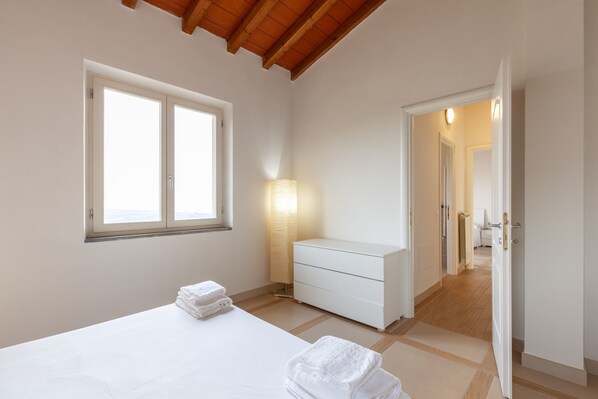 Un dormitorio con cama, mesita de noche, lámpara, cómoda y ventana.
