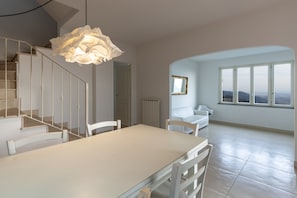 A spacious room with a dining table, chairs, a staircase, a large window with a view, and a unique ceiling light fixture. - Villa 'Martina' with Pool and Terrace, Pet-Friendly (Pietrasanta)