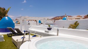 A rooftop pool area with lounge chairs, a hot tub, and a view of buildings in the background. - Vacation Home "Villa 82" with Mountain View, Pool & Wi-Fi (Corralejo)