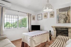 Une chambre avec un lit, une télévision, une cheminée et des tableaux encadrés accrochés au mur.