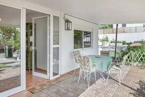 Une terrasse avec une table et des chaises, une porte-fenêtre coulissante et une vue sur la rue.