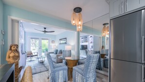A modern kitchen with a stainless steel refrigerator, a dining area with patterned chairs, and a glass-top table. - Ahoy Mate! with Compass Realty at the Truman Annex in Key West (Key West)
