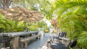 An outdoor patio with a table, chairs, and an umbrella. - Ahoy Mate! with Compass Realty at the Truman Annex in Key West (Key West)