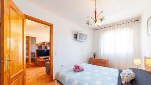 Une chambre à coucher comprenant un lit, une télévision, un bureau et une armoire.