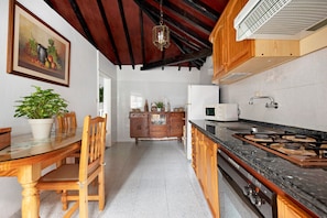 A kitchen with wooden cabinets, a gas stove, a microwave, and a dining area with a table and chairs.